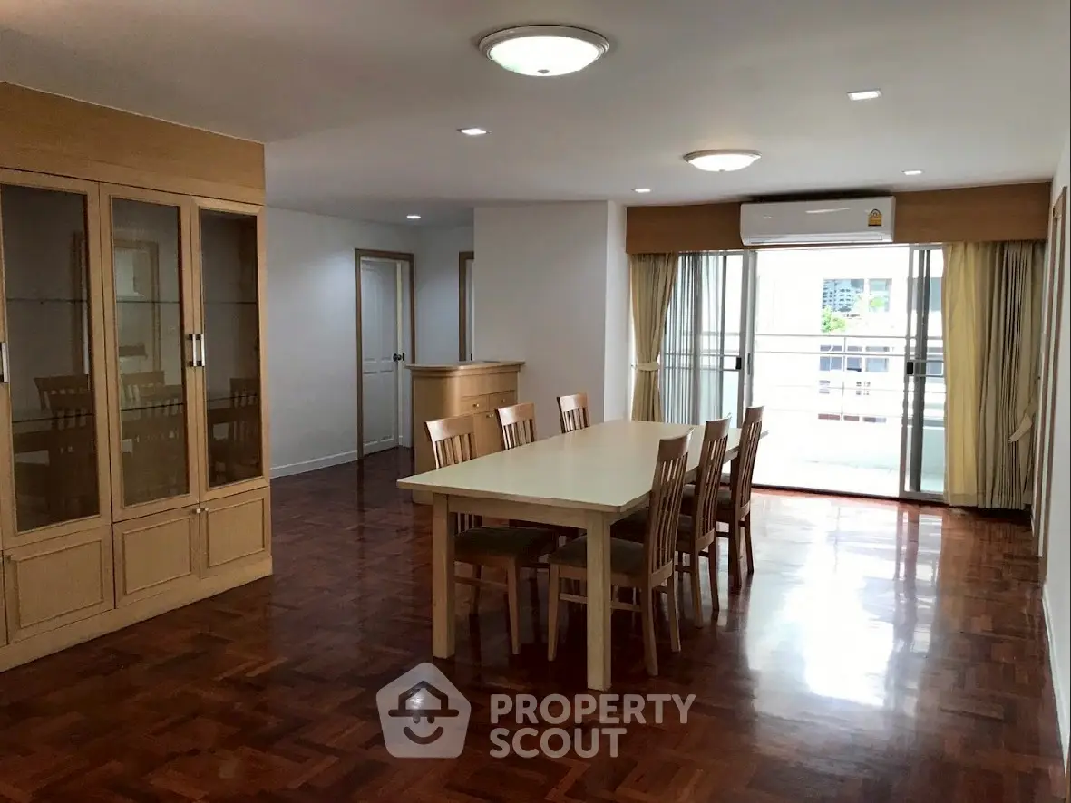 Spacious dining area with wooden flooring and large windows for natural light.