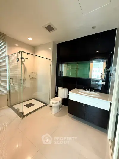 Modern bathroom with glass shower and sleek black and white design.