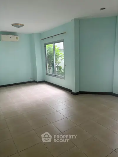 Spacious empty room with large window and air conditioning, ideal for customization.