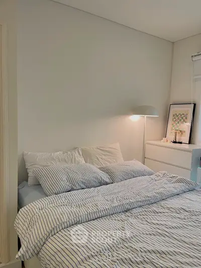 Cozy bedroom with striped bedding and modern lamp