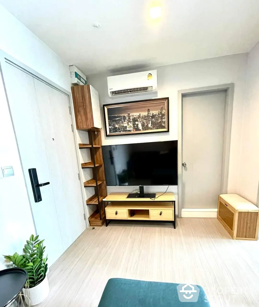 Modern and cozy living room with sleek TV unit, wooden shelving, and minimalist decor, perfect for urban living.