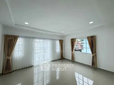 Spacious empty room with large windows and elegant curtains, perfect for customization.
