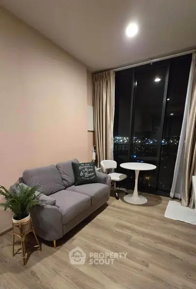 Modern living room with cozy sofa and city view through large windows, perfect for relaxation.