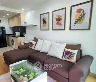 Modern living room with stylish decor and open kitchen layout, featuring a cozy brown sofa and vibrant wall art.