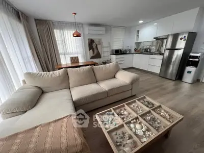 Modern open-layout living room with cozy beige sofa and stylish kitchen area.