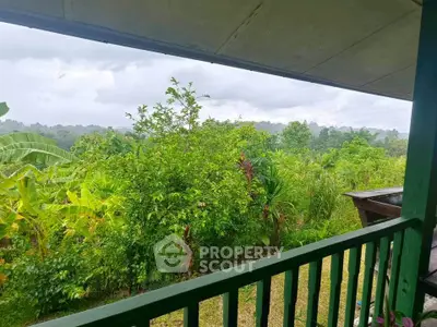 Scenic view from a covered balcony overlooking lush greenery and distant hills, perfect for nature lovers.