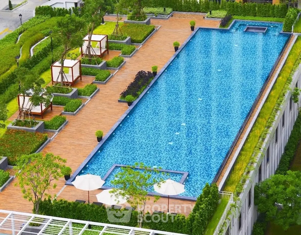 Luxurious rooftop pool with cabanas and lush greenery in modern residential complex.