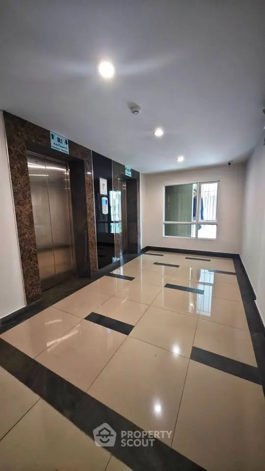 Modern building lobby with polished tile flooring and elevator access.