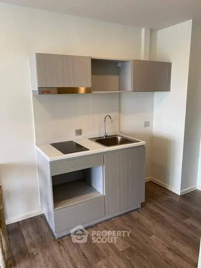 Modern compact kitchen with sleek cabinetry and wood flooring, perfect for urban living.
