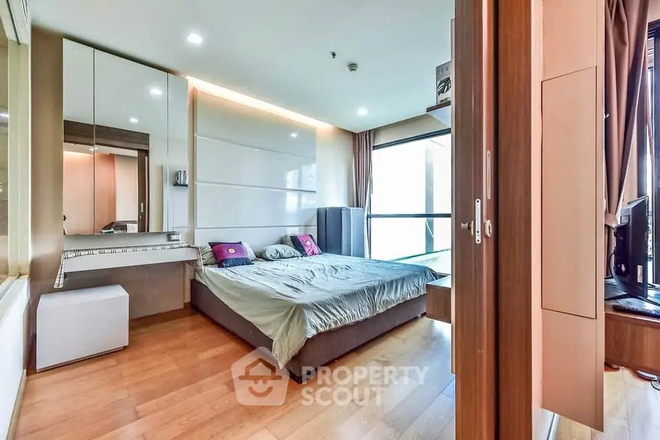 Spacious modern bedroom with wooden flooring and large windows in a stylish apartment.