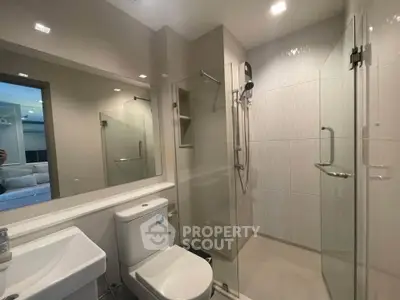 Modern bathroom with glass shower and sleek fixtures in contemporary apartment.