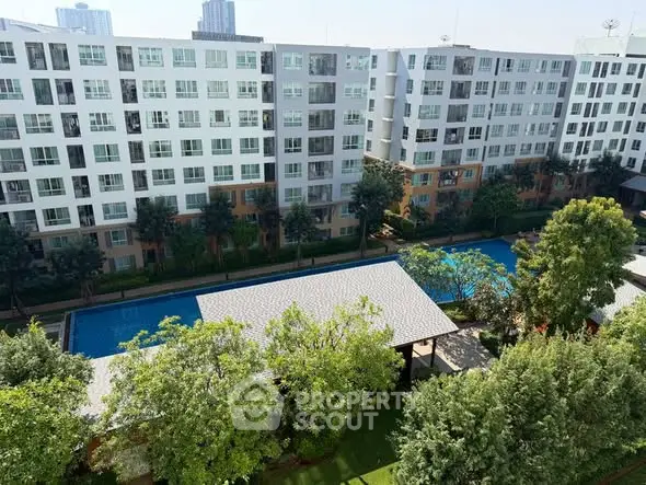 Modern apartment complex with pool and lush greenery, ideal urban living.