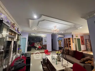 Luxurious living room with elegant ceiling design and chandelier, featuring modern furniture and decor.