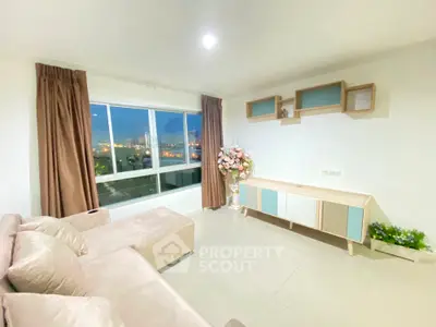 Spacious living room with large windows offering a stunning city view, complemented by modern furnishings and tasteful decor.
