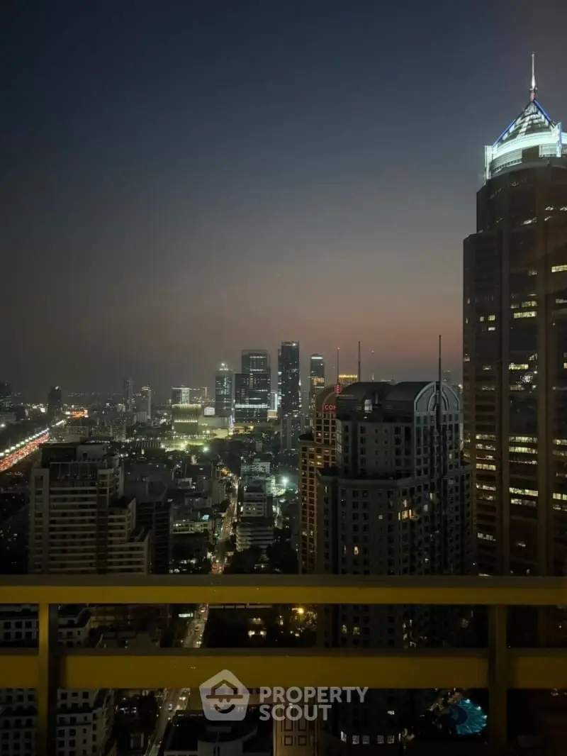 Stunning cityscape view from a high-rise balcony at dusk, showcasing urban skyline and vibrant lights.