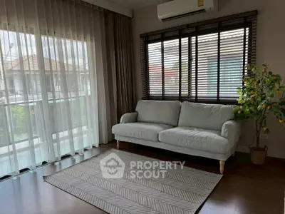 Bright living room with large windows, cozy sofa, and stylish decor in modern home.