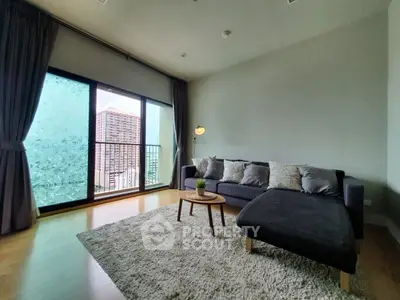 Spacious living room with large window and modern furniture in a high-rise apartment.