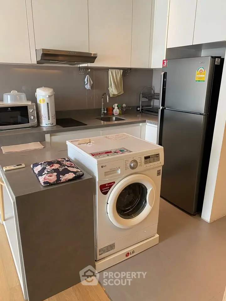 Modern kitchen with sleek appliances and integrated washing machine in a stylish apartment.