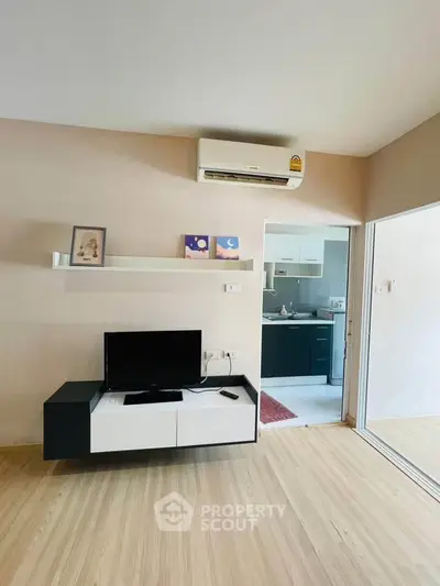Modern living room with sleek TV stand and air conditioning, adjacent to a stylish kitchen.