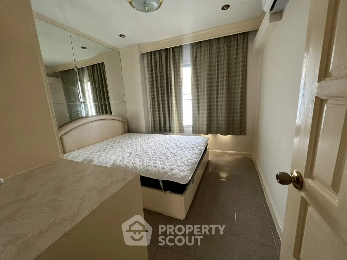 Cozy bedroom with mirrored closet and large window for natural light.