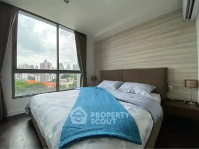 Spacious bedroom with large window offering stunning city views, modern decor, and cozy ambiance.