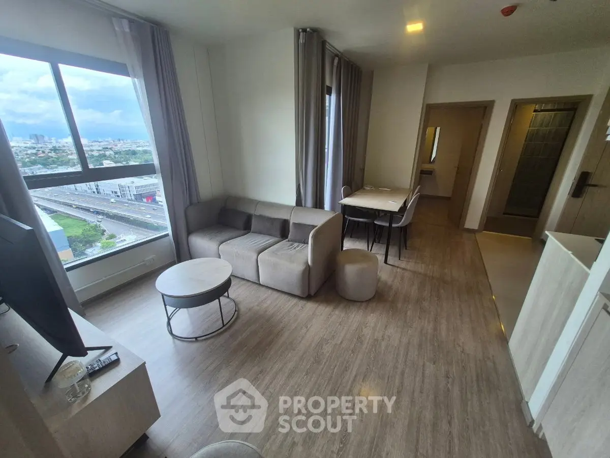 Modern living room with city view, stylish furniture, and natural light.