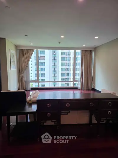 Spacious living room with large windows offering a stunning city view, elegant wooden flooring, and modern decor.