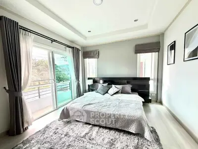 Spacious bedroom with large windows and balcony access, featuring modern decor and abundant natural light.