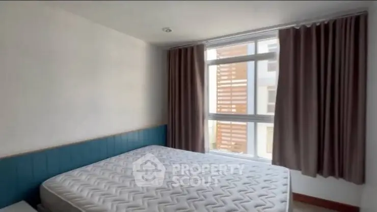 Spacious bedroom with large window and modern design in prime real estate location.