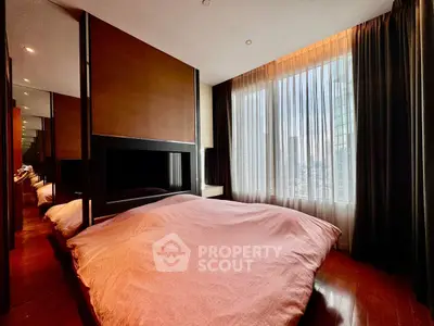 Luxurious bedroom with large window offering stunning city views, elegant decor, and ample natural light.