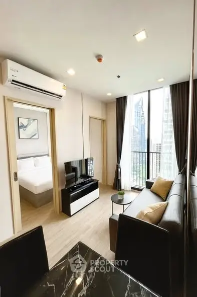 Modern living room with city view, featuring sleek furniture and large windows in a high-rise apartment.