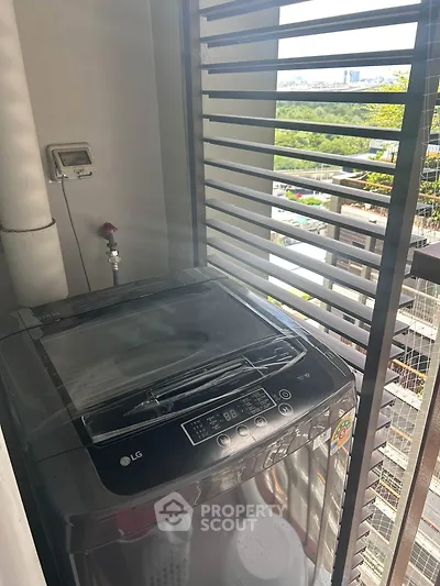Compact balcony with washing machine and city view, perfect for urban living convenience.