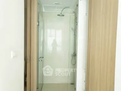 Modern bathroom with glass shower enclosure and sleek wooden accents.