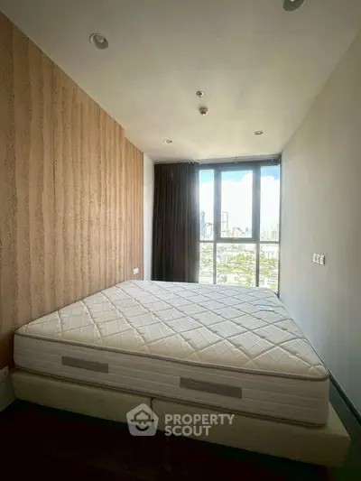 Spacious bedroom with large window offering stunning city views, featuring a comfortable bed and modern decor.