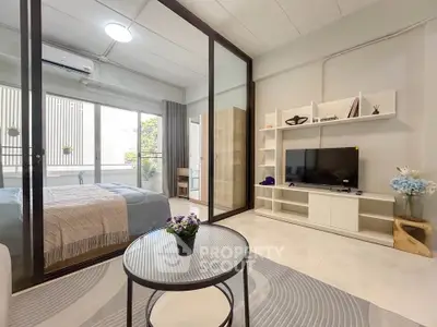 Modern studio apartment with open layout, featuring a cozy living area and stylish bedroom separated by glass doors.