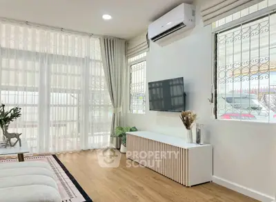 Modern living room with sleek design, featuring a wall-mounted TV and air conditioning.