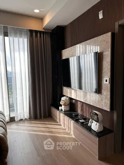Modern living room with large TV and stylish decor, featuring floor-to-ceiling windows and elegant curtains.