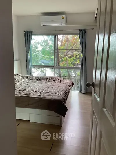 Cozy bedroom with large window and natural light, featuring a comfortable bed and air conditioning.