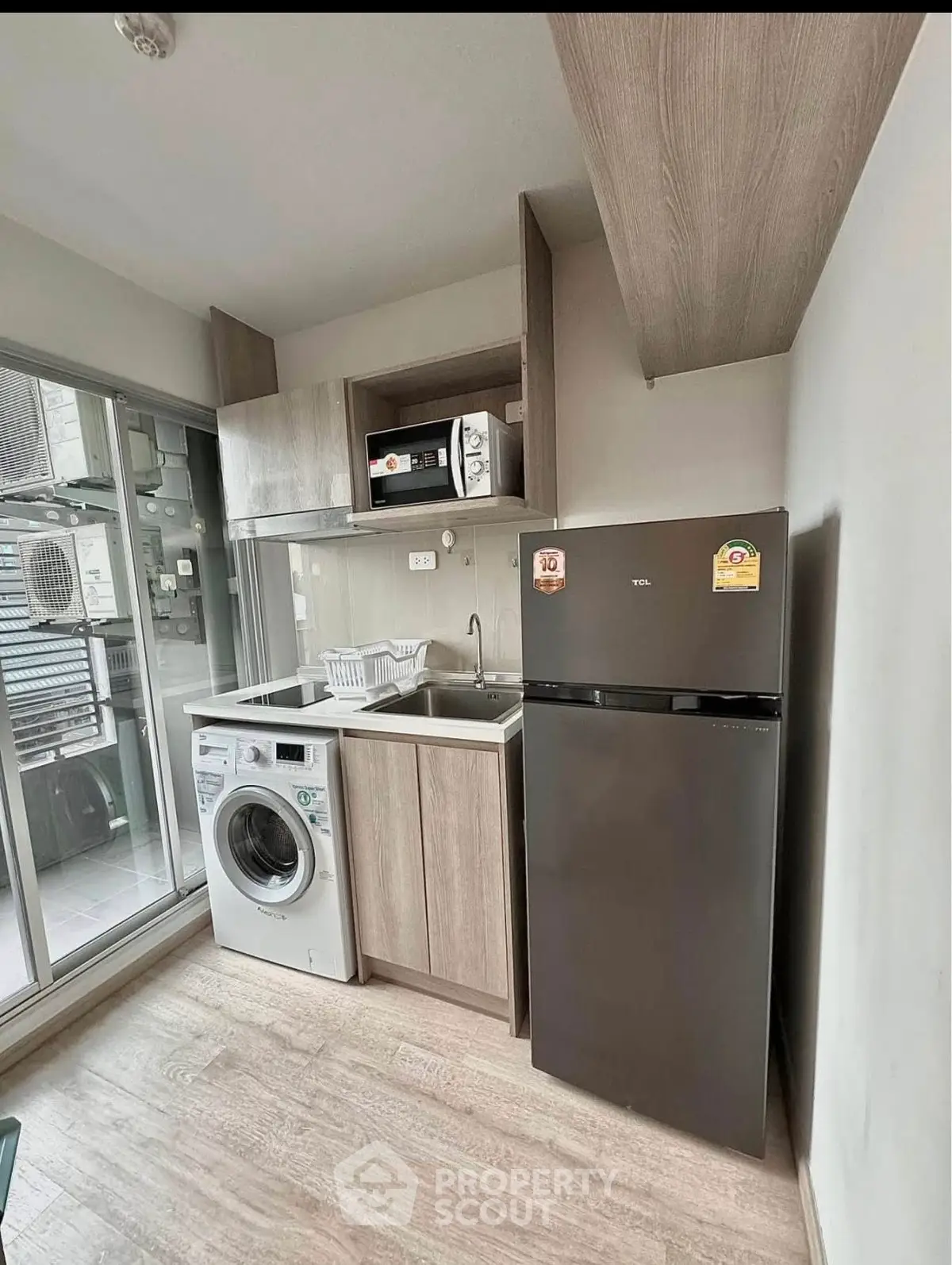Compact kitchen with modern appliances including fridge, microwave, and washing machine.