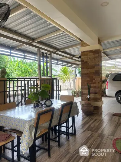 Spacious covered patio with dining area and carport in a tropical setting.