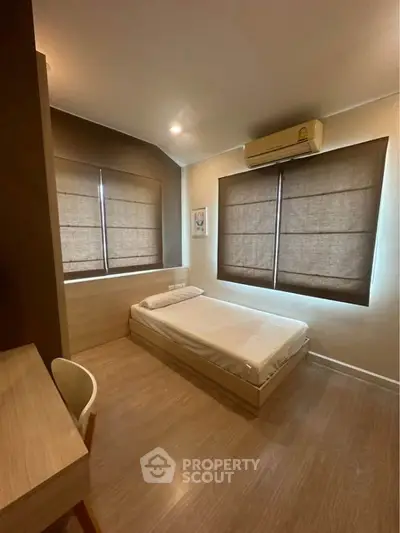Cozy minimalist bedroom with wooden flooring and modern air conditioning unit.