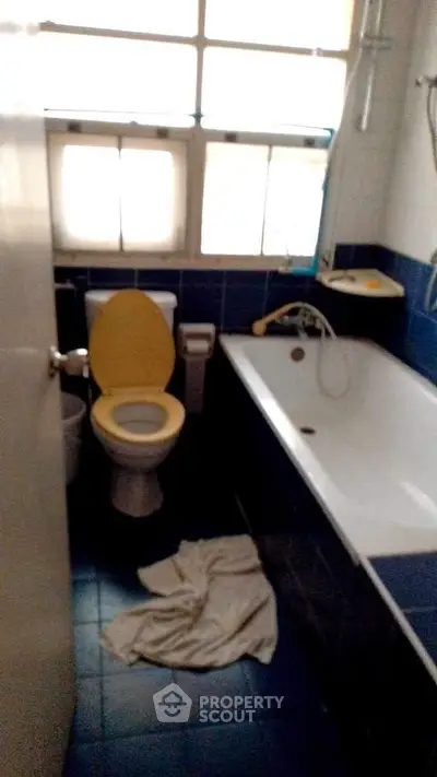 Cozy bathroom with bathtub and blue tile accents, perfect for relaxation.