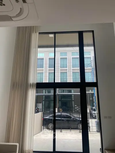Spacious modern living room with floor-to-ceiling windows offering a view of the urban landscape.