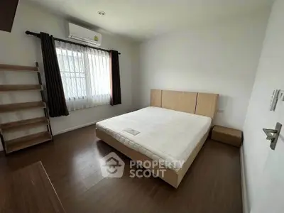 Spacious bedroom with wooden flooring and modern furnishings in a bright apartment.