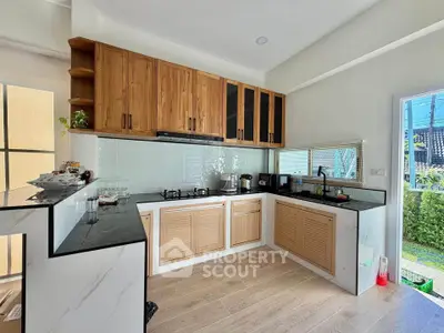 Modern kitchen with wooden cabinets and open layout, featuring gas stove and garden view.