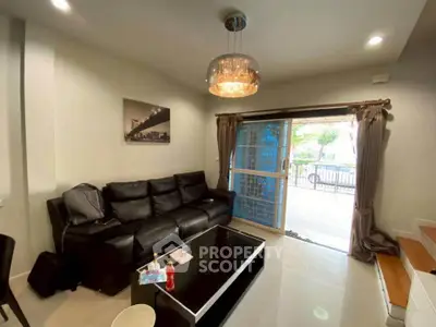 Modern living room with black leather sofa and sliding glass doors to patio.