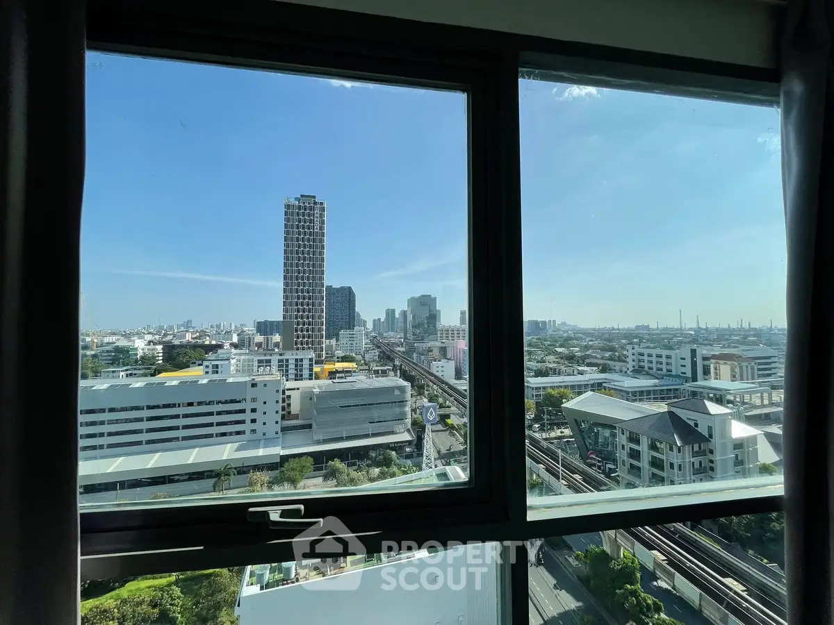 Stunning cityscape view from high-rise apartment window with clear blue sky.