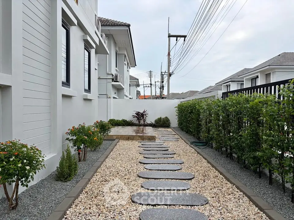 Modern residential exterior with landscaped garden and stone pathway, showcasing elegant design and curb appeal.