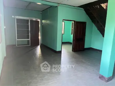 Spacious interior with tiled flooring and staircase, ideal for customization.