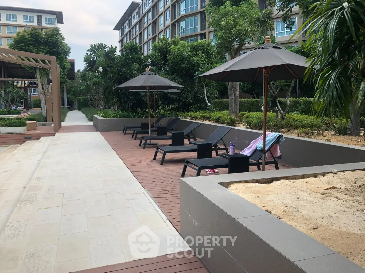 Luxurious poolside area with sun loungers and umbrellas in a modern residential complex.